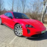 Czerwony Porsche Taycan GTS na brukowanym podjeździe, gotowy do jazdy.