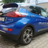 Błękitny Chevrolet Bolt EV z napisem "Powered by GM electric engine" na klapie bagażnika.