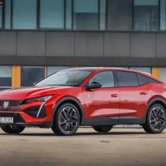 Czerwony Peugeot 408 na parkingu, zgrabnie prezentujący swoje wymiary i dynamiczną sylwetkę.