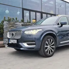 Elegancki, ciemnoszary Volvo XC90 T8 z nowoczesnymi światłami LED stoi przed budynkiem z dużymi, przeszklonymi oknami.