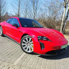 Czerwony Porsche Taycan GTS na brukowanym podjeździe, gotowy do jazdy.