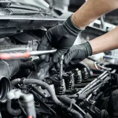 Mechanik naprawia zatarty silnik, używając klucza do dokręcenia części. Olej 0w20 mógł być przyczyną problemu.