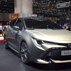 Elegancki, srebrny Auris Hybrid prezentowany na targach motoryzacyjnych. Na podłodze widoczny napis "NEW AURIS WORLD PREMIERE".