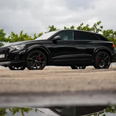 Czarny Audi Q9, lśniący po deszczu, z czerwonymi zaciskami hamulcowymi. Zastanawiasz się nad audi q9 cena?