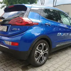 Błękitny Chevrolet Bolt EV z napisem "Powered by GM electric engine" na klapie bagażnika.