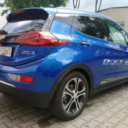 Błękitny Chevrolet Bolt EV z napisem "Powered by GM electric engine" na klapie bagażnika.