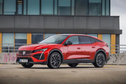 Czerwony Peugeot 408 na parkingu, zgrabnie prezentujący swoje wymiary i dynamiczną sylwetkę.