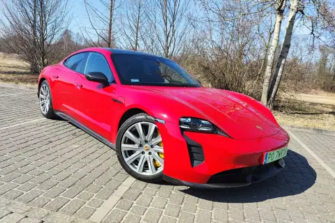 Czerwony Porsche Taycan GTS na brukowanym podjeździe, gotowy do jazdy.