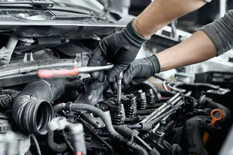Mechanik naprawia zatarty silnik, używając klucza do dokręcenia części. Olej 0w20 mógł być przyczyną problemu.