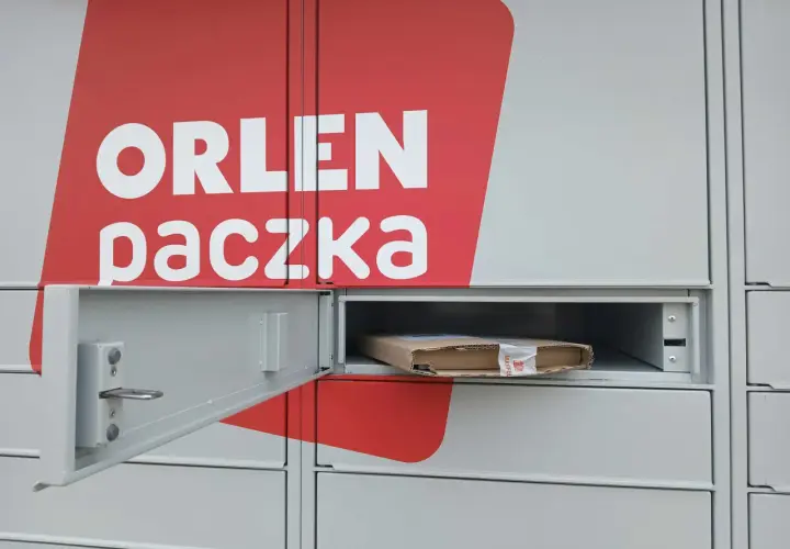 Szafka paczkomatu z logo Orlen Paczka i paczką w środku.