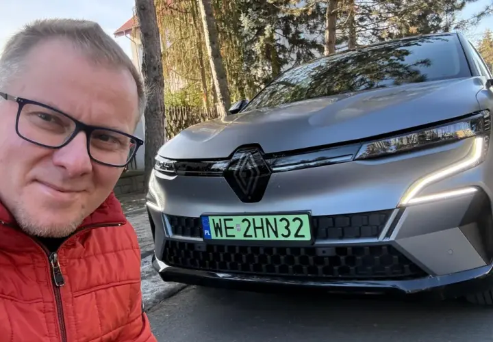 Mężczyzna w czerwonej kurtce robi selfie z nowym Renault Megane E-Tech.