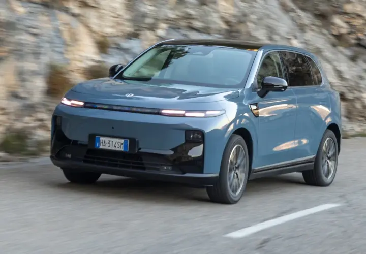 Niebieski Leapmotor B10 przemierza krętą drogę wśród skalistych zboczy.
