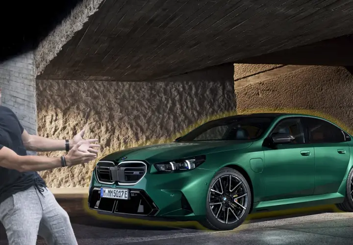 Mężczyzna z entuzjazmem prezentuje zielone BMW G90 pod betonowym zadaszeniem.