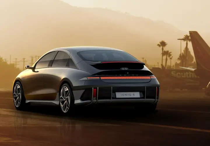 Elegancki Hyundai Ioniq 6 z charakterystycznym pasem świateł z tyłu, zaparkowany na tle lotniska i palm.