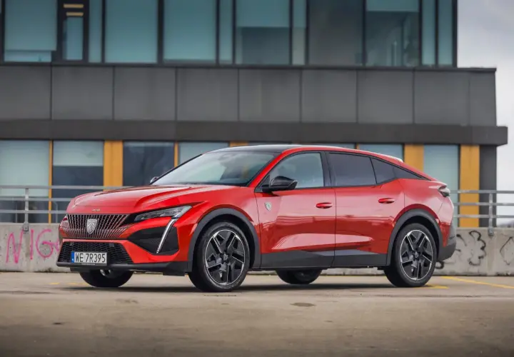 Czerwony Peugeot 408 na parkingu, zgrabnie prezentujący swoje wymiary i dynamiczną sylwetkę.