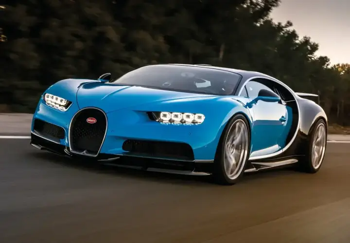 Niebieski Bugatti Chiron pędzi po drodze. Jego cena jest astronomiczna, ale wrażenia z jazdy bezcenne.