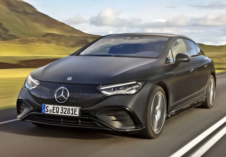 Elegancki, czarny Mercedes EQE sunie po drodze wśród malowniczych wzgórz.