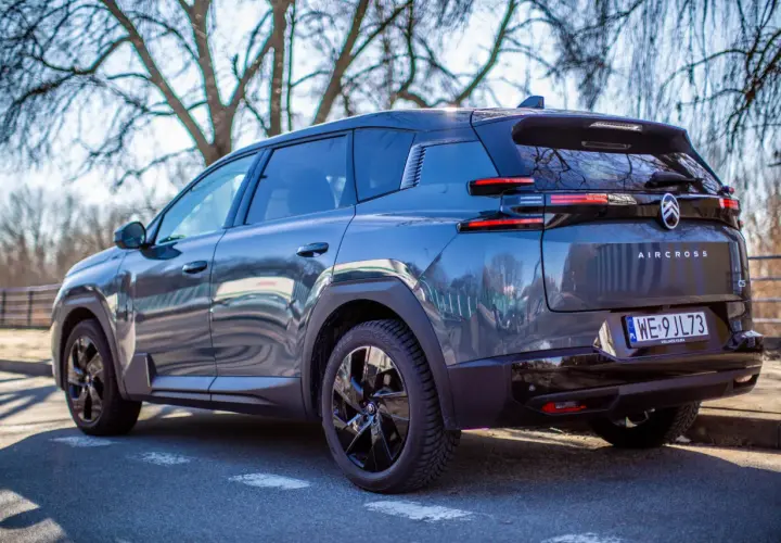 Ciemnoszary Citroën C5 Aircross Hybrid zaparkowany pod drzewami. Widok z tyłu, z tablicą rejestracyjną WE 9JL73.