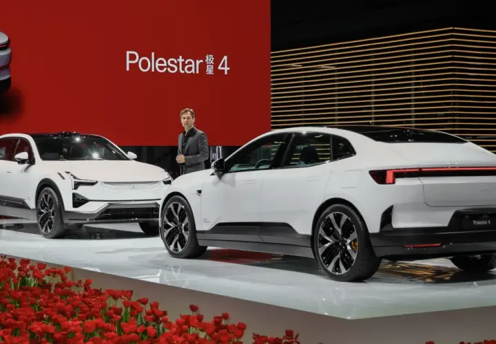 Dwa białe samochody Polestar 4 na scenie z czerwonym tłem i tulipanami.