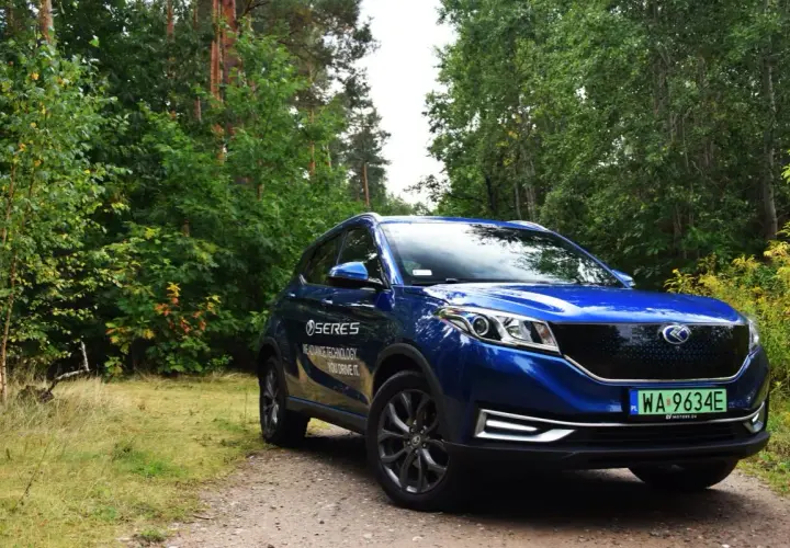 Niebieski SUV Seres 3 na leśnej drodze.