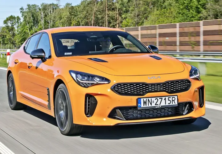 Pomarańczowy Kia Stinger na drodze. Sprawdź aktualną kia stinger cena i możliwości tego sportowego sedana.