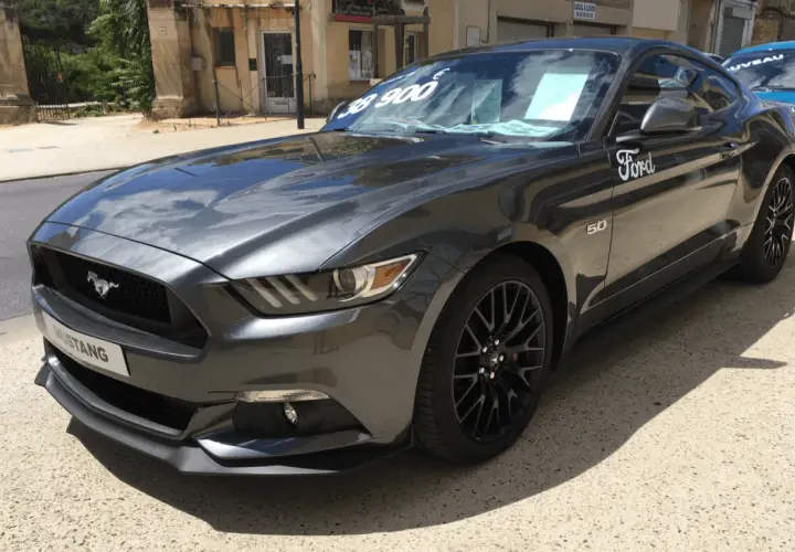 Szary Ford Mustang GT 5.0 z ceną 38 900 na szybie, gotowy do jazdy.