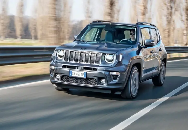 Ciemnoszary Jeep Renegade Hybrid jedzie po drodze, za kierownicą siedzi mężczyzna w okularach.