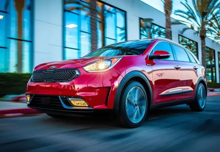Czerwony Kia Niro Hybrid w ruchu, z palmami i nowoczesnym budynkiem w tle.