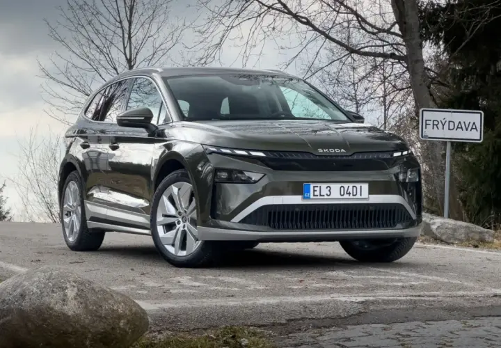 Zielony Skoda Enyaq na drodze, obok znaku "FRÝDAVA". Sprawdź atrakcyjną skoda enyaq cena.