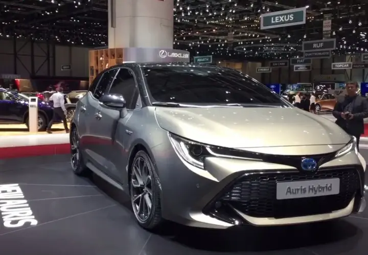 Elegancki, srebrny Auris Hybrid prezentowany na targach motoryzacyjnych. Na podłodze widoczny napis "NEW AURIS WORLD PREMIERE".