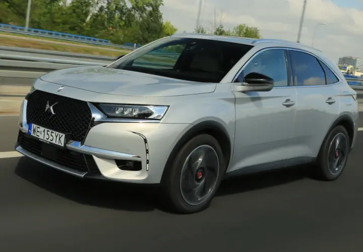 Srebrny DS 7 Crossback E-Tense pędzi autostradą, jego elegancka linia podkreślona przez dynamiczne światła.