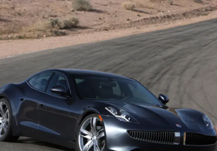 Elegancki, ciemnoszary Fisker Karma na torze wyścigowym, z pustynnym krajobrazem w tle.