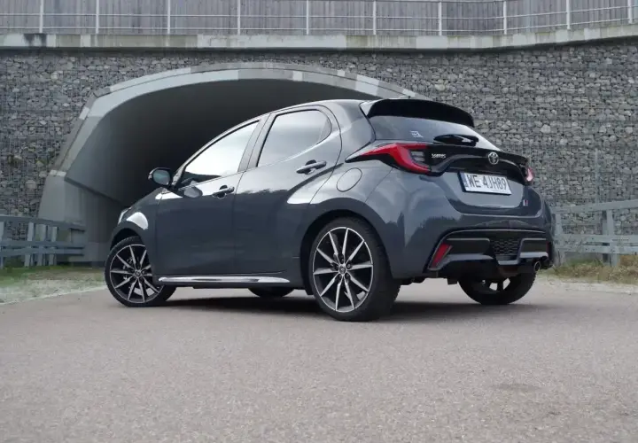 Ciemnoszary Toyota Yaris Hybrid z nowoczesnymi felgami stoi przed betonowym tunelem.