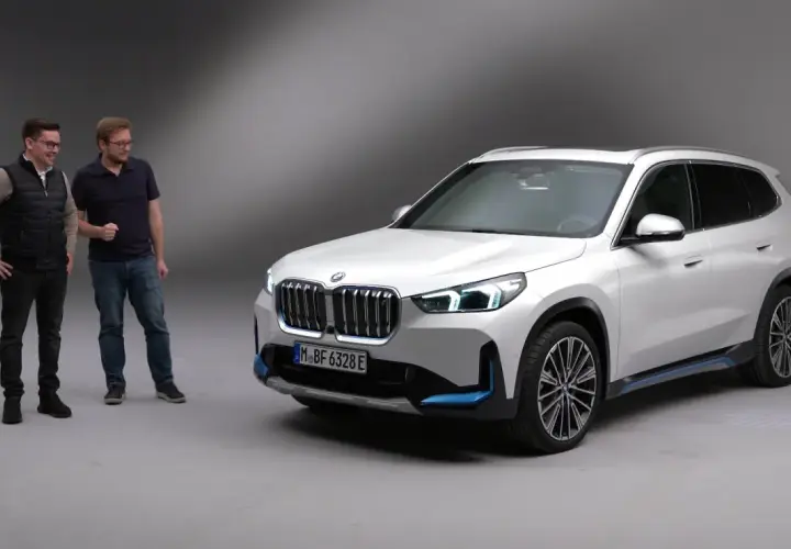 Dwóch mężczyzn obok białego BMW X1 elektryk.