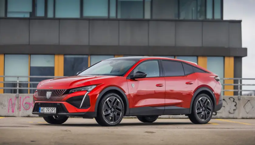 Czerwony Peugeot 408 na parkingu, zgrabnie prezentujący swoje wymiary i dynamiczną sylwetkę.