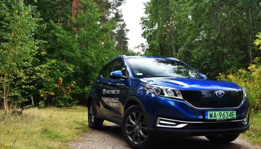 Niebieski SUV Seres 3 na leśnej drodze.