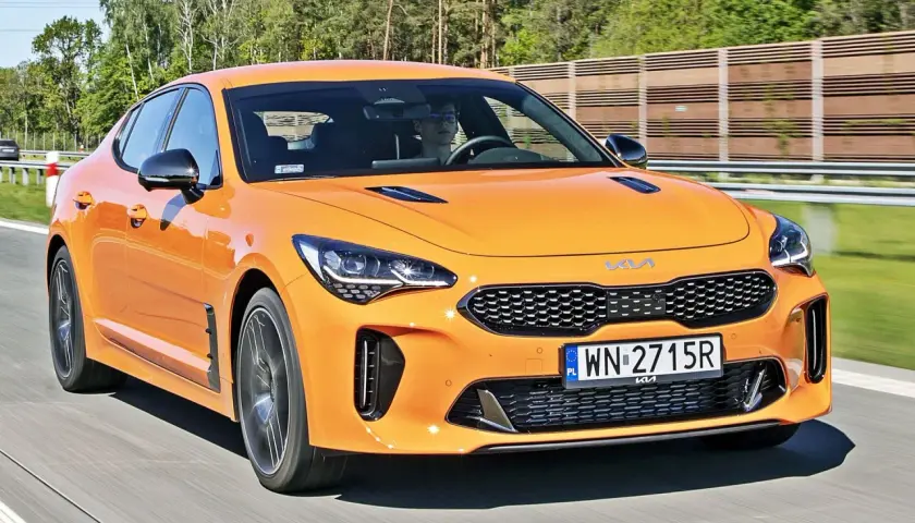 Pomarańczowy Kia Stinger na drodze. Sprawdź aktualną kia stinger cena i możliwości tego sportowego sedana.