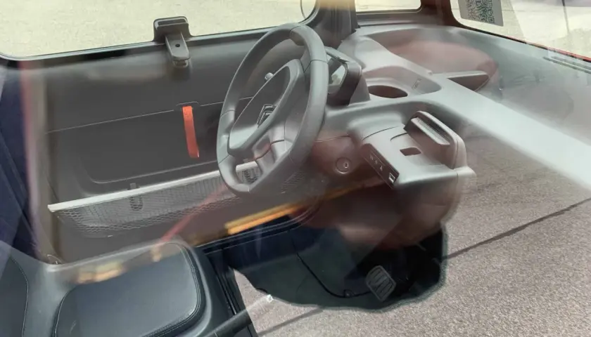 Wnętrze Citroen Ami: kierownica, siedzenie, deska rozdzielcza z uchwytem i panelem sterowania.