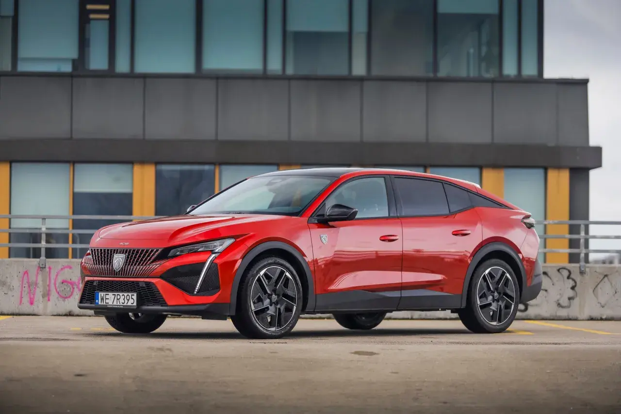 Czerwony Peugeot 408 na parkingu, zgrabnie prezentujący swoje wymiary i dynamiczną sylwetkę.