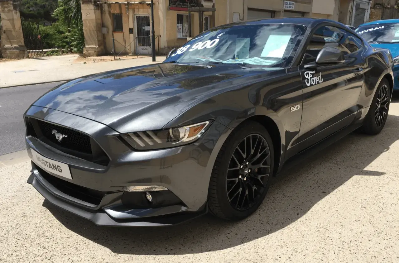 Szary Ford Mustang GT 5.0 z ceną 38 900 na szybie, gotowy do jazdy.