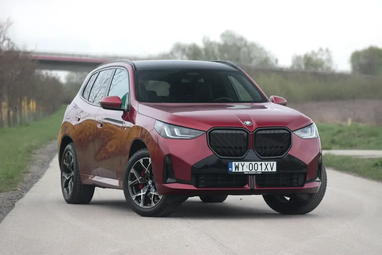Czerwone BMW X3 30e z czarnymi dodatkami i felgami stoi na drodze.
