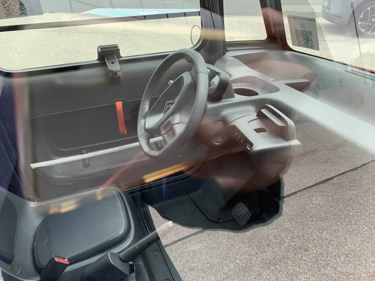 Wnętrze Citroen Ami: kierownica, siedzenie, deska rozdzielcza z uchwytem i panelem sterowania.