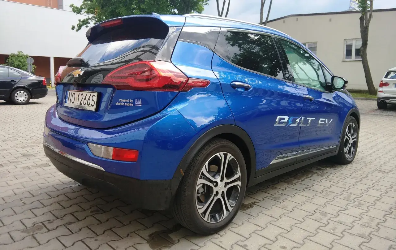 Błękitny Chevrolet Bolt EV z napisem "Powered by GM electric engine" na klapie bagażnika.