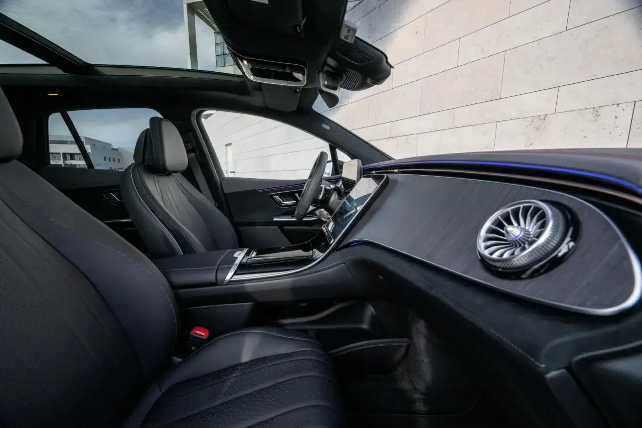 Wnętrze luksusowego EQE Mercedes z panoramicznym dachem i nowoczesnym panelem.