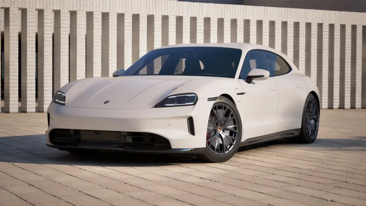 Biały Porsche Taycan GTS z ciemnymi felgami stoi przed nowoczesnym budynkiem z białej cegły.
