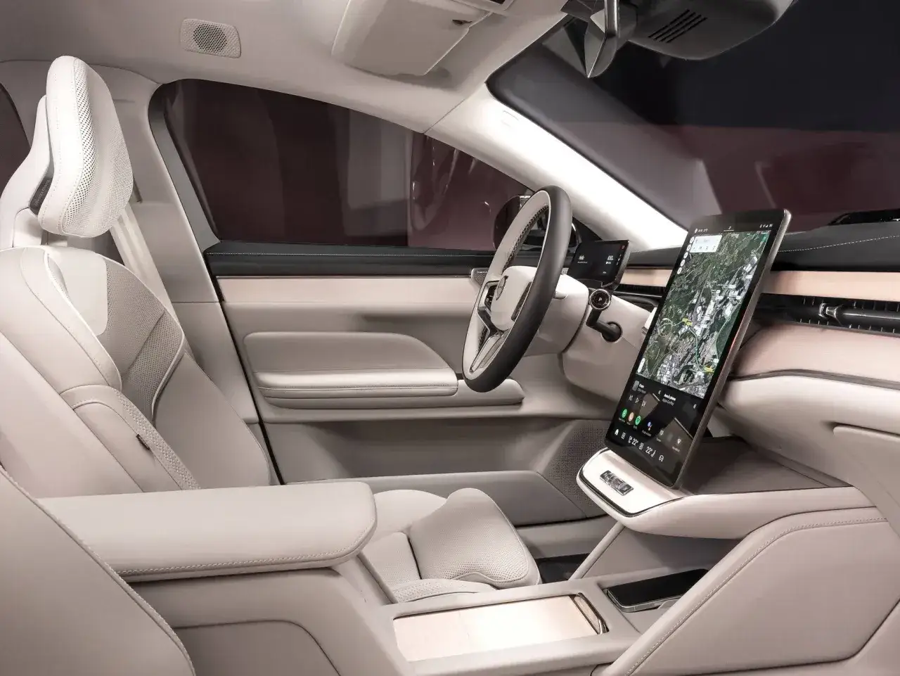 Wnętrze Volvo EX90: jasne, skórzane fotele, duży ekran multimedialny z nawigacją i drewniane akcenty tworzą luksusową atmosferę.