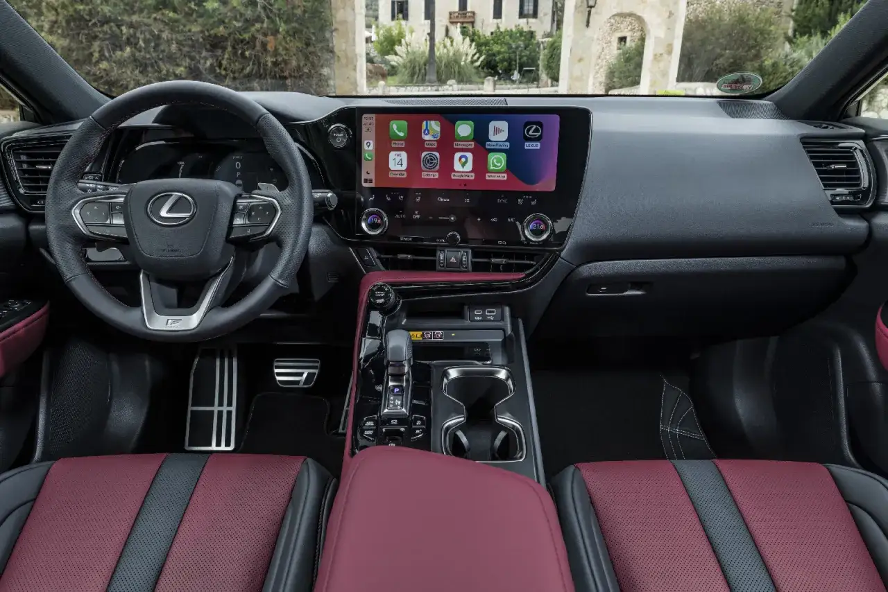 Wnętrze Lexus NX 350h z ekranem multimedialnym, kierownicą i czerwono-czarnymi fotelami.