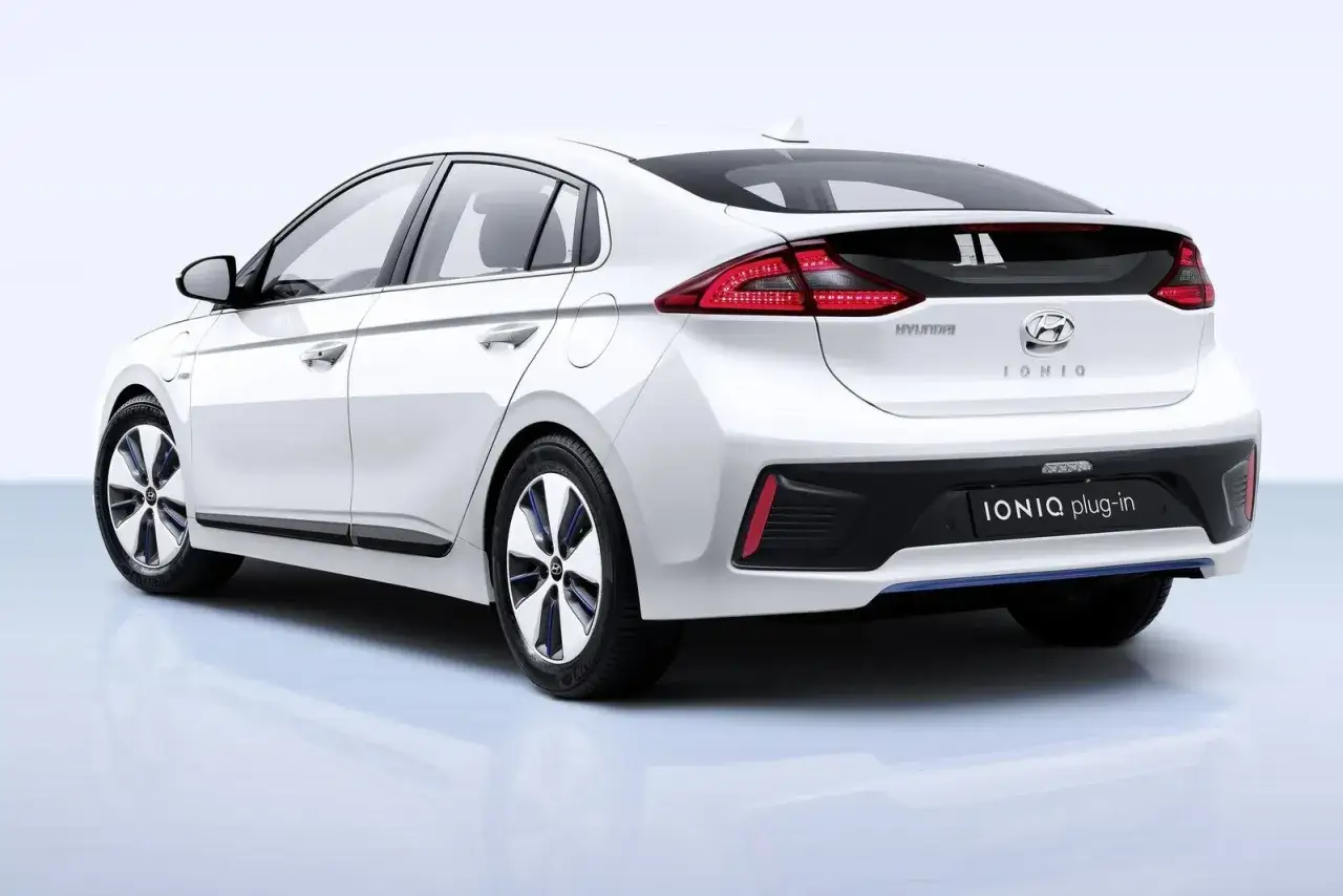 Biały Hyundai Ioniq Plug-in, hybrydowy samochód z niebieskimi akcentami na felgach, prezentuje się elegancko.