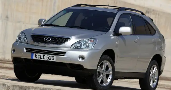 Srebrny Lexus RX 400h z przyciemnianymi szybami i relingami dachowymi, zaparkowany na betonowym podłożu.